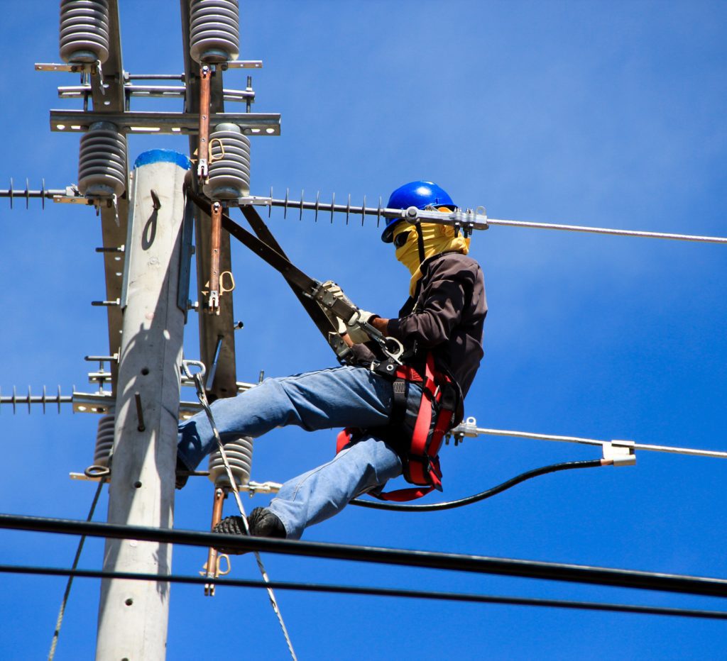 An electrical worker does maintenance on a utility pole.