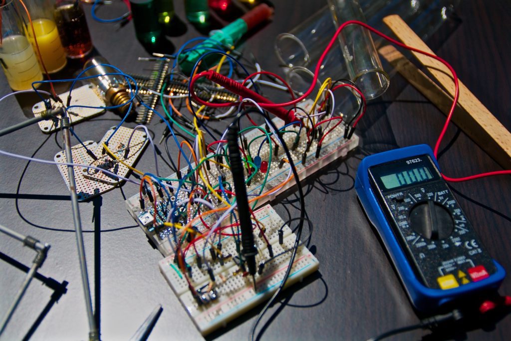 An image of an electronic circuit board next to a tester.