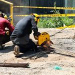 Two construction workers with helmets and ear protection, kneeling and cutting rails with a circular saw.