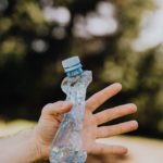 A hand holding an empty, crushed plastic water bottle.