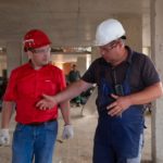 A construction manager and a contractor conversing on the job site.