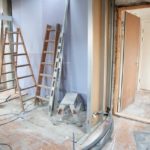 A room in the midst of being remodeled with ladders and siding scattered throughout.