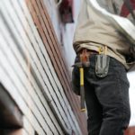 A handyman getting to perform work on the side of a house.