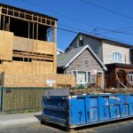 Rental dumpster on street in front of house under construction.