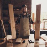 Handyman standing at work bench with a board in each hand